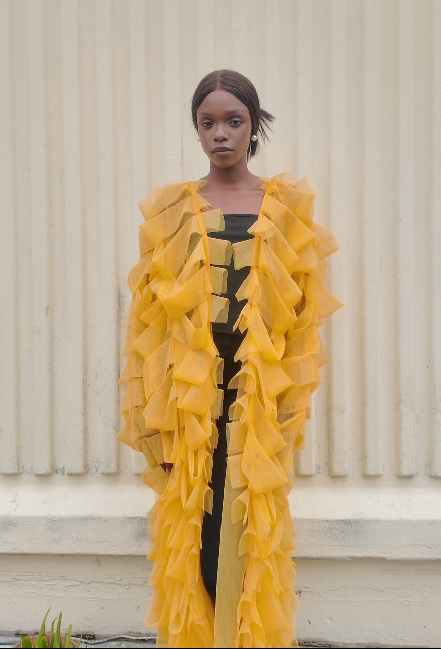 Person wearing a bright yellow ruffled outfit against a neutral background